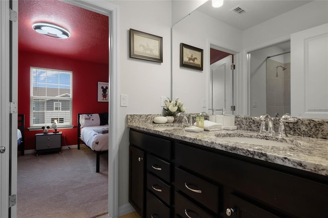 ensuite bathroom with a sink, double vanity, visible vents, and connected bathroom