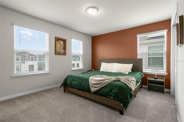 bedroom with light carpet, baseboards, and multiple windows