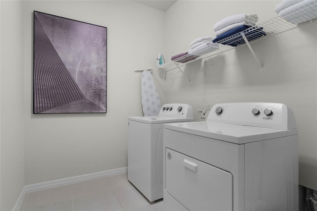 clothes washing area featuring light tile patterned floors, laundry area, washing machine and clothes dryer, and baseboards