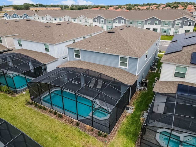 pool featuring glass enclosure, a residential view, and a yard