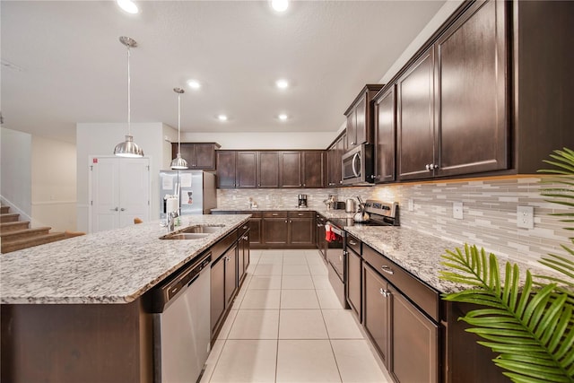 4149 Lana Ave, Davenport, FL 33897 - kitchen featuring appliances with stainless steel finishes, a sink, dark brown cabinetry, a center island with sink, and tasteful backsplash