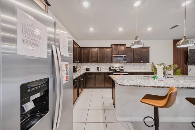 4149 Lana Ave, Davenport, FL 33897 - kitchen with stainless steel appliances, a sink, dark brown cabinets, tasteful backsplash, and light stone counters