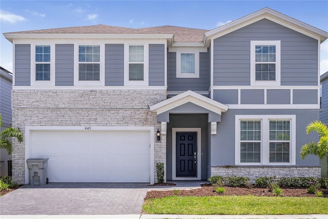 4149 Lana Ave, Davenport, FL 33897 - view of front of property featuring stone siding, decorative driveway, and a garage