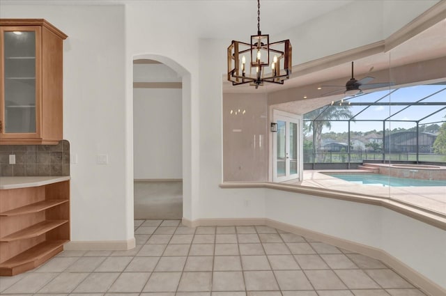 10616 Emerald Chase Dr, Orlando, FL 32836 - unfurnished dining area featuring arched walkways, a sunroom, light tile patterned flooring, ceiling fan, and baseboards