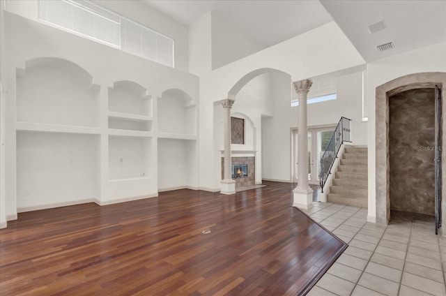10616 Emerald Chase Dr, Orlando, FL 32836 - unfurnished living room featuring decorative columns, a tiled fireplace, stairway, wood finished floors, and a high ceiling