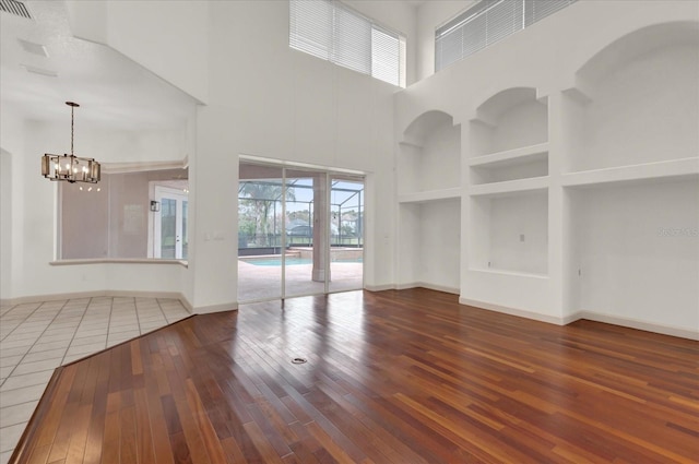 10616 Emerald Chase Dr, Orlando, FL 32836 - spare room featuring baseboards, built in shelves, wood finished floors, and an inviting chandelier
