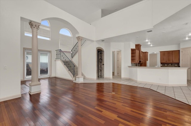 10616 Emerald Chase Dr, Orlando, FL 32836 - unfurnished living room with baseboards, light wood-style flooring, stairway, a high ceiling, and ornate columns