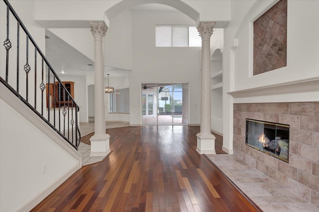 10616 Emerald Chase Dr, Orlando, FL 32836 - unfurnished living room featuring a tile fireplace, baseboards, ornate columns, and wood finished floors