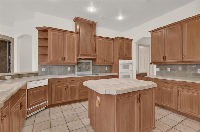 10616 Emerald Chase Dr, Orlando, FL 32836 - kitchen with black electric cooktop, tile counters, a center island, open shelves, and custom range hood
