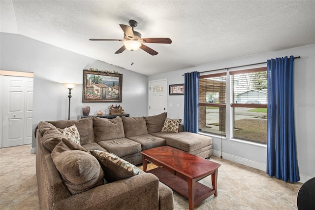 living room featuring vaulted ceiling, a textured ceiling, baseboards, and ceiling fan