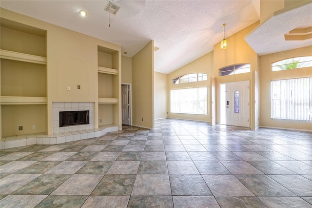 unfurnished living room featuring visible vents, a textured ceiling, a wealth of natural light, and built in features