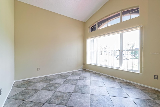 tiled spare room featuring baseboards, vaulted ceiling, and a textured ceiling