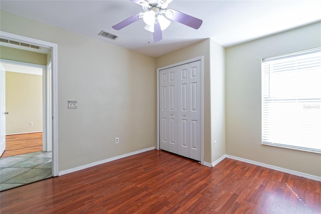 unfurnished bedroom featuring visible vents, dark wood finished floors, and multiple windows