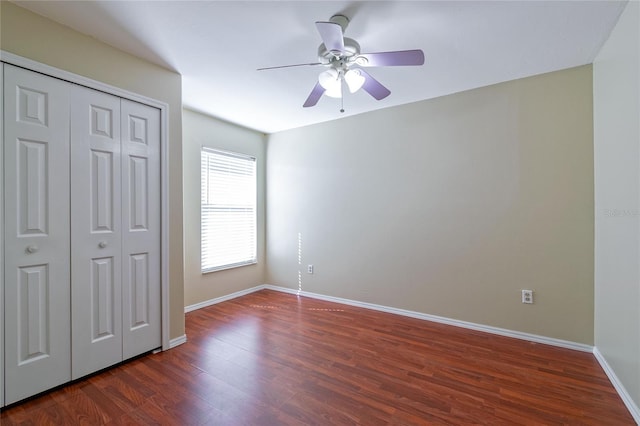 unfurnished bedroom with dark wood-style floors, a closet, a ceiling fan, and baseboards