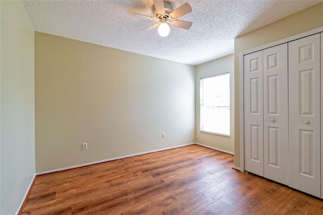 unfurnished bedroom featuring baseboards, ceiling fan, wood finished floors, a textured ceiling, and a closet