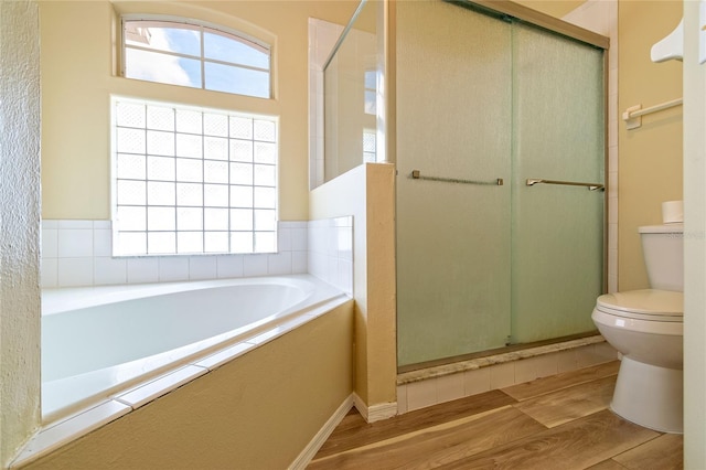 full bath featuring a bath, wood finished floors, a shower stall, and toilet