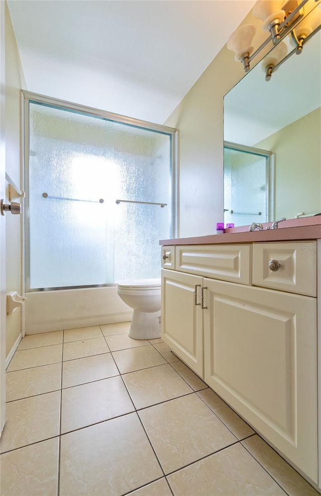 bathroom with combined bath / shower with glass door, vanity, toilet, and tile patterned floors