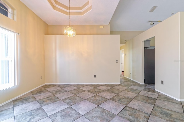 spare room featuring a notable chandelier, plenty of natural light, and baseboards