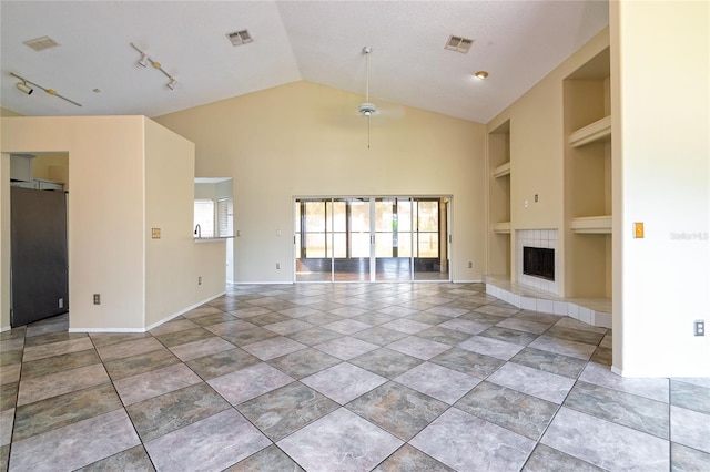 unfurnished living room with built in features, rail lighting, visible vents, and a tiled fireplace