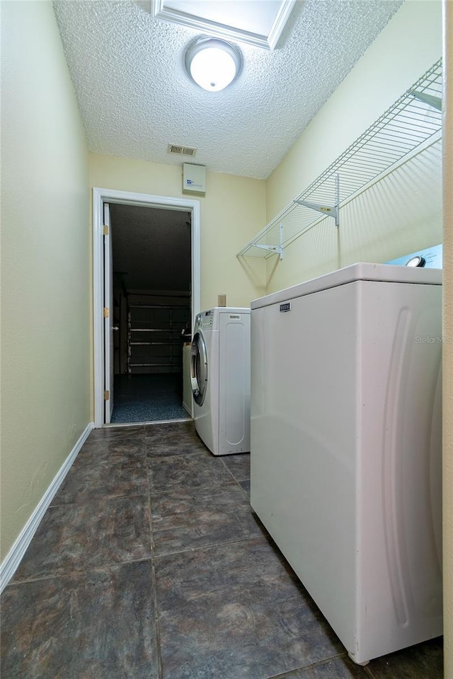 clothes washing area with laundry area, visible vents, a textured ceiling, and separate washer and dryer