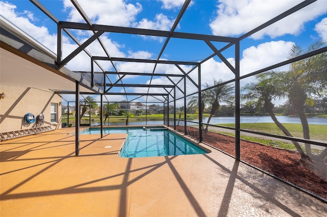 outdoor pool featuring glass enclosure, a patio, and a water view