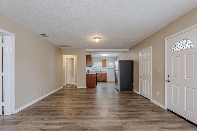 kitchen featuring visible vents, open floor plan, freestanding refrigerator, brown cabinets, and dark wood-style floors