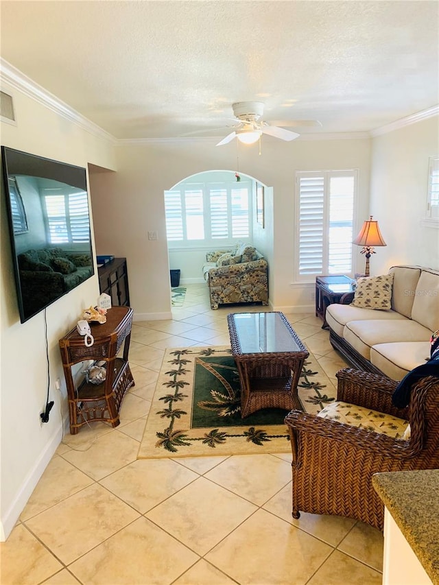 living area featuring a textured ceiling, ornamental molding, light tile patterned floors, and baseboards