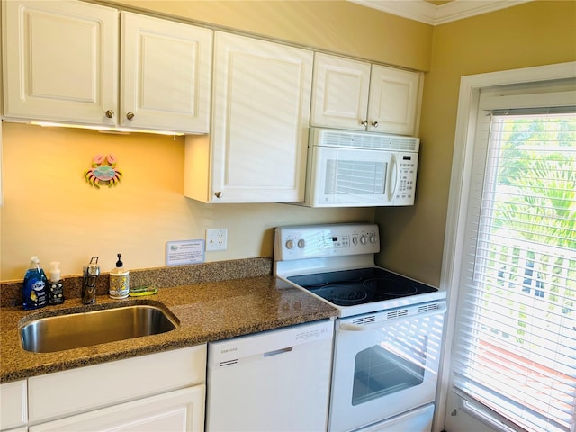 kitchen with ornamental molding, white cabinets, a sink, dark stone countertops, and white appliances