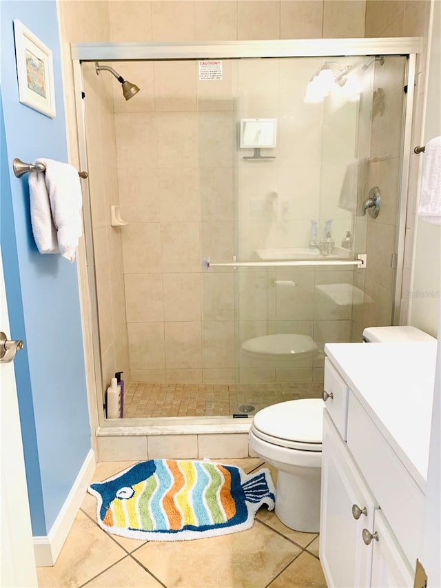 bathroom with a shower stall, vanity, toilet, and tile patterned floors