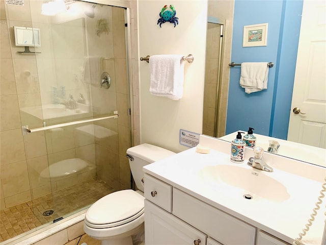 bathroom featuring a shower stall, toilet, and vanity