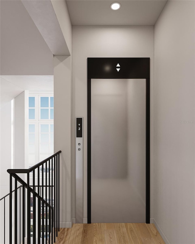 corridor with elevator, recessed lighting, wood finished floors, and an upstairs landing