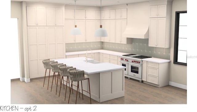 kitchen with white cabinets, range with two ovens, a kitchen island with sink, light countertops, and a sink