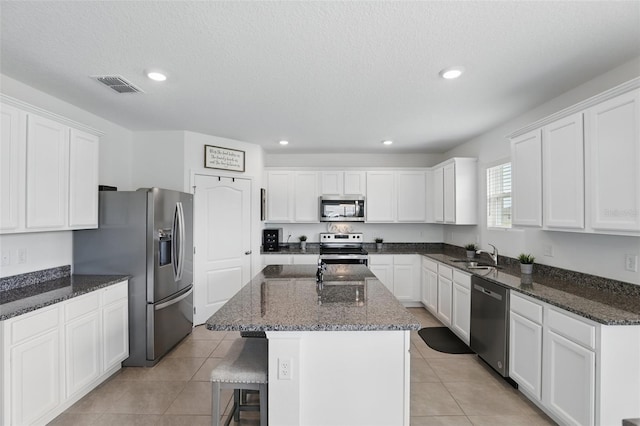 kitchen with a breakfast bar, a sink, visible vents, white cabinets, and appliances with stainless steel finishes