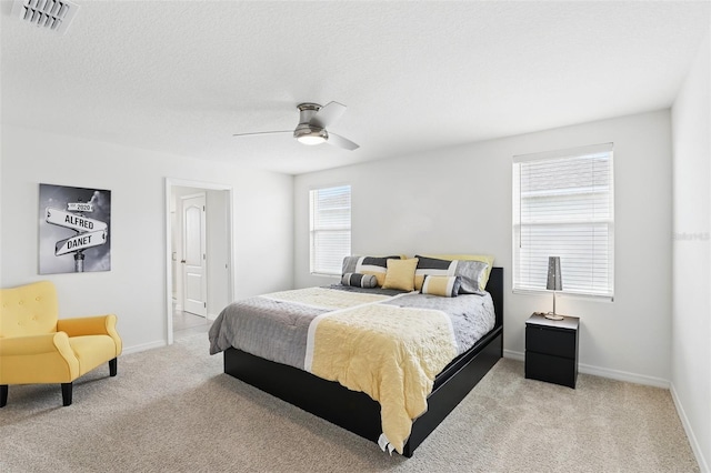 bedroom with a textured ceiling, carpet flooring, visible vents, and baseboards