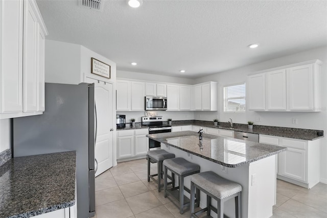 kitchen featuring a sink, visible vents, white cabinets, appliances with stainless steel finishes, and a kitchen bar