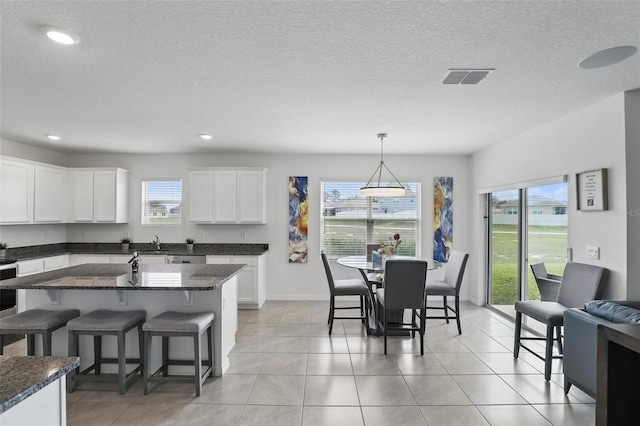 kitchen featuring light tile patterned floors, white cabinetry, visible vents, and a breakfast bar area