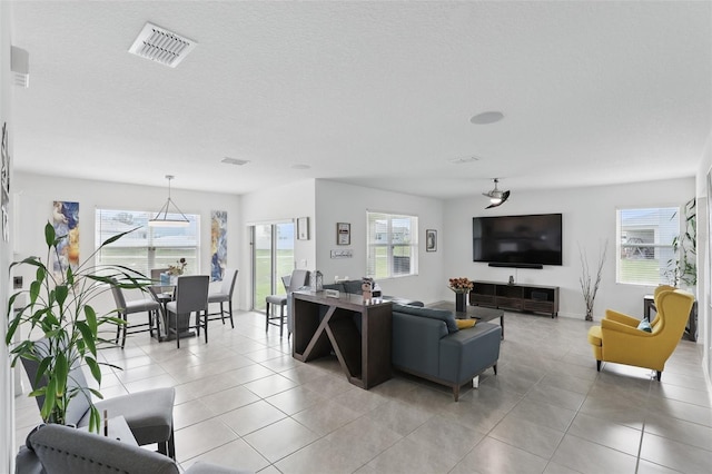 living area featuring light tile patterned floors, a textured ceiling, and visible vents