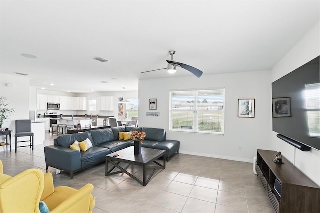 living room featuring light tile patterned floors, ceiling fan, visible vents, and baseboards