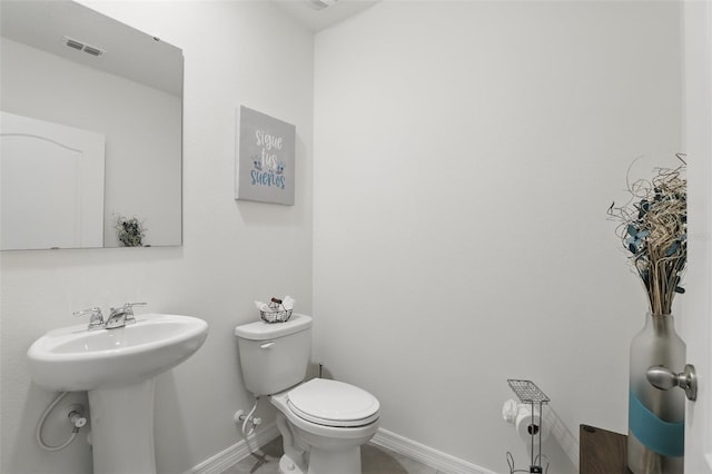 half bath with baseboards, visible vents, a sink, and toilet