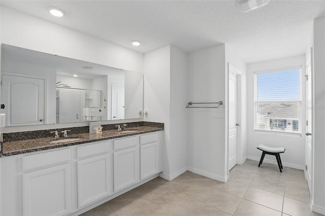 bathroom with a stall shower, a sink, baseboards, and double vanity