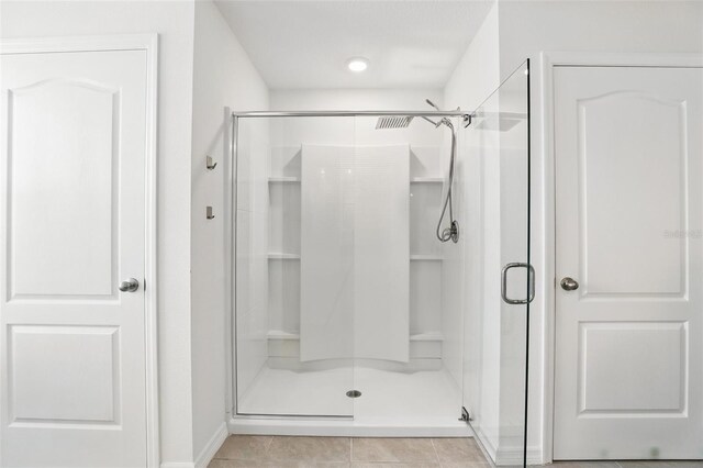 full bathroom with tile patterned flooring and a shower stall