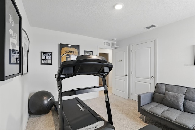 exercise area with a textured ceiling, visible vents, and light colored carpet