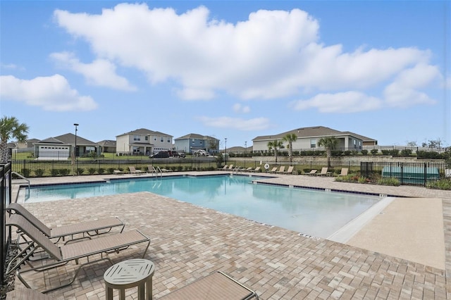 pool with a residential view, fence, and a patio