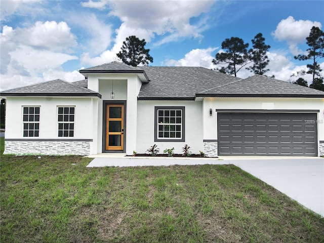 prairie-style house with stucco siding, concrete driveway, an attached garage, a front yard, and stone siding