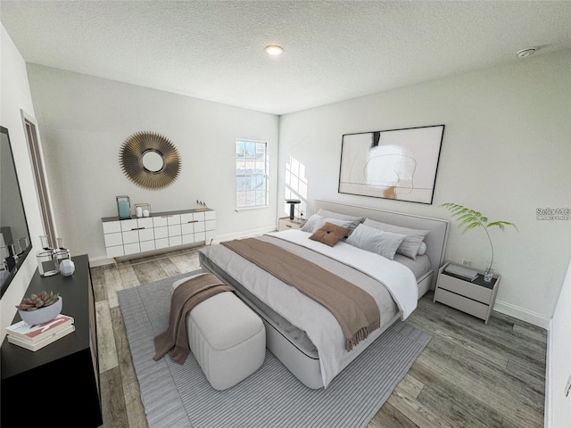 bedroom with a textured ceiling, baseboards, and wood finished floors