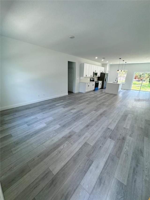 unfurnished living room with light wood finished floors and baseboards