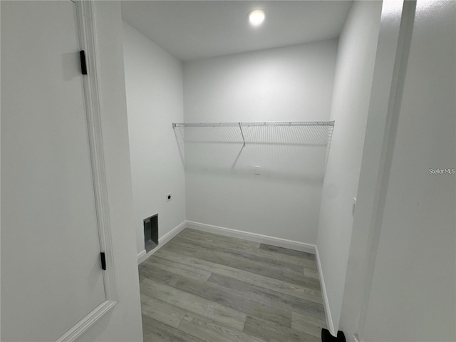 clothes washing area featuring light wood-style floors, visible vents, electric dryer hookup, and baseboards