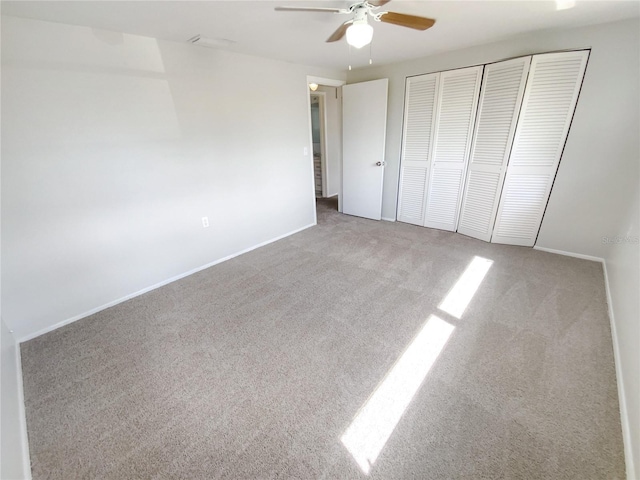 unfurnished bedroom with light carpet, ceiling fan, a closet, and baseboards