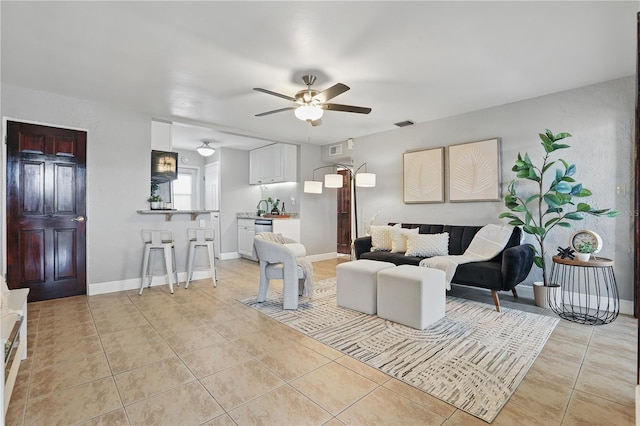 living room featuring light tile patterned flooring, ceiling fan, and baseboards