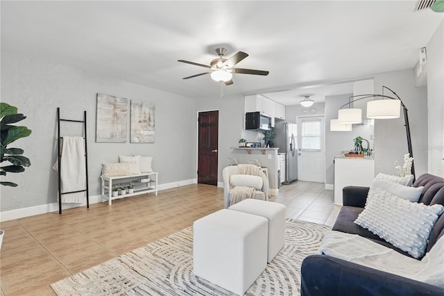 living area featuring a ceiling fan, light tile patterned flooring, visible vents, and baseboards